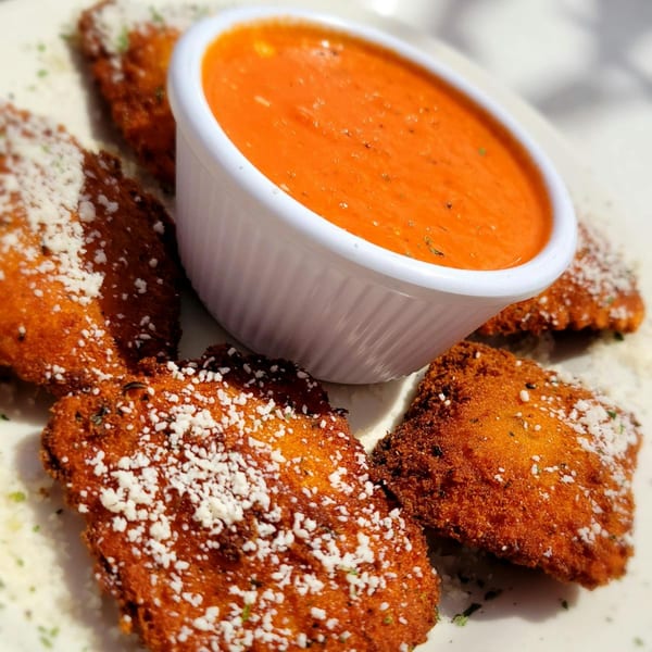 Golden-brown fried ravioli, sprinkled with Parmesan cheese and herbs, served with a side of red marinara sauce.