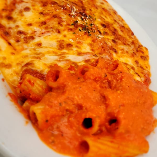 Baked ziti pasta with melted cheese and red sauce on a white plate.