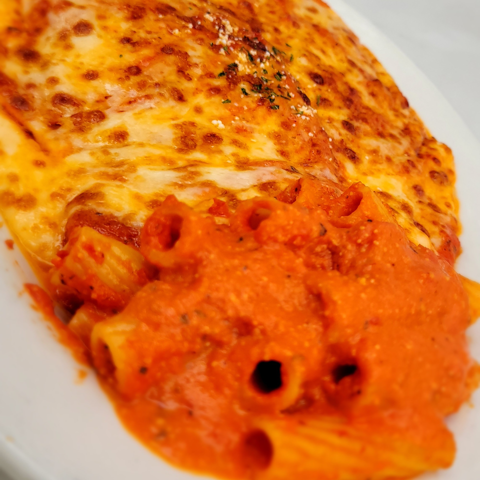 Baked ziti pasta with melted cheese and red sauce on a white plate.
